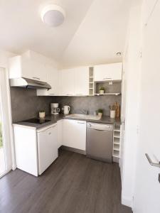 a white kitchen with white cabinets and a sink at Charmant studio avec piscine 4 personnes in Fréjus