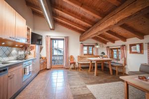 a kitchen with wooden ceilings and a table in a room at Bergbauernhof Simmerl in Sachrang