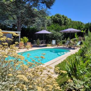 a swimming pool in a yard with umbrellas at chambres d'hôtes BARTAV aile in Espeluche