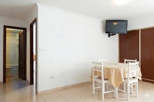 a dining room with a table and a tv on a wall at Pensión Rey in Isla de Arosa