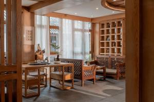 a dining room with a table and chairs and windows at Lijiang Cloud Return Huiyi · On the Water Side Panoramic Hidden Inn (South Gate Mufu Branch) in Lijiang
