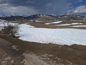 a snow covered field with mountains in the background at Autocamp Kotari in Plužine +2 photos