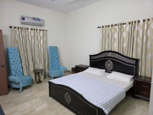 a bedroom with a bed and two blue chairs at UrbanNOOK Basic in Rawalpindi