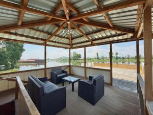 a screened porch with chairs and a table and a view of a river at Lord Palace Houseboat in Srinagar