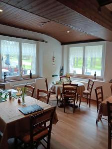 a dining room with tables and chairs and windows at Pension Waldegg Zermeiggern in Saas-Almagell