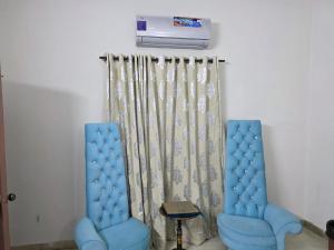 two blue chairs sitting next to a wall with a heater at UrbanNOOK Basic in Rawalpindi