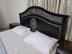a bed with a black headboard and white pillows at UrbanNOOK Basic in Rawalpindi