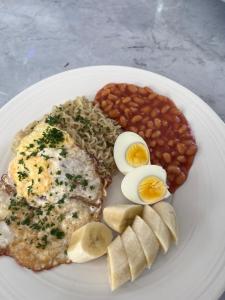a plate of food with eggs beans and bread at Sumanya guest house 3 in Sukuta
