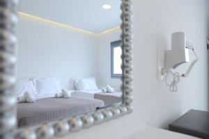 ein Spiegel, der zwei Betten in einem Zimmer reflektiert in der Unterkunft Tinamar Selections in Perivolos