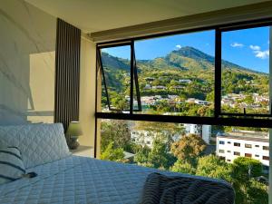 a bedroom with a large window with a mountain view at Panoramic view apartment with Pool and Rooftop in San Salvador