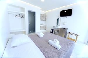 ein Schlafzimmer mit einem großen weißen Bett, auf dem Handtücher liegen in der Unterkunft Tinamar Selections in Perivolos