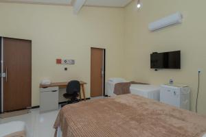 a room with two beds and a desk and a tv at Pousada Biana Residence in Santo Amaro
