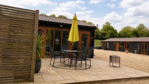 a patio with a table and a yellow umbrella at Converted Barn Studio with Private En-Suite in Horspath