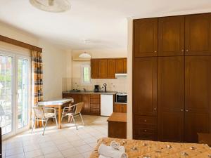 a kitchen with wooden cabinets and a table with chairs at Celestine Apartment, Arillas, Korfu in Arillas