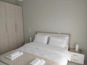 a bedroom with a white bed with two towels on it at Claudia's Apartments in Aliveri +16 photos