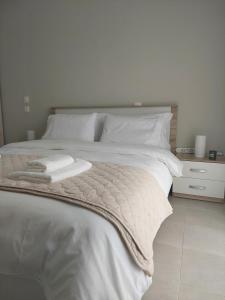 a white bed with a blanket and a night stand at Claudia's Apartments in Aliveri