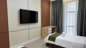 a hotel room with a bed and a flat screen tv at Zafran Platinum Apartments in Dushanbe