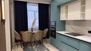 a kitchen with a table with chairs and a window at Zafran Platinum Apartments in Dushanbe
