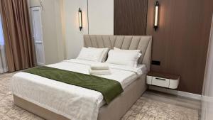 a bedroom with a large bed with white sheets at Zafran Platinum Apartments in Dushanbe