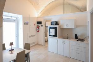a kitchen with white cabinets and a table and a dining room at Dimora Donizzetti in Martina Franca