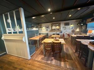 a restaurant with wooden tables and chairs in a room at Lochindaal Hotel in Port Charlotte