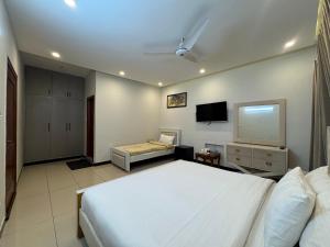 a bedroom with a white bed and a flat screen tv at Bridge Residency in Islamabad