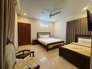 a hotel room with two beds and a chair at Bridge Residency in Islamabad