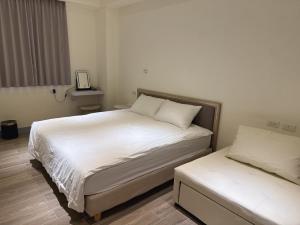 a bedroom with two beds with white sheets and a tv at Musun Stay in Ch'ao-yang