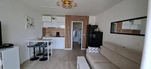 a living room with a couch and a table and a kitchen at Vertige Bleu, Vue mer, Port, Plage, WI-FI, Clim, Centre ville, Commerces, Calme in La Grande Motte +8 photos