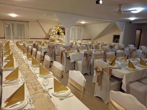a banquet hall with white tables and white chairs at Cserki Panzió Balatonfőkajár in Balatonfőkajár