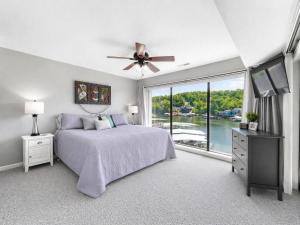 a bedroom with a bed with a ceiling fan and a window at Serenity Pointe Boat Slip in Osage Beach