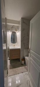 a white bathroom with a sink and a mirror at Vertige Bleu, Vue mer, Port, Plage, WI-FI, Clim, Centre ville, Commerces, Calme in La Grande Motte