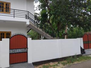 a white fence in front of a building with red doors at CaReville Chunnakam in Chunnakam