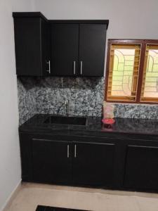 a kitchen with black cabinets and a sink at CaReville Chunnakam in Chunnakam +5 photos