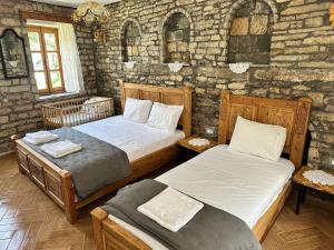 a bedroom with two beds and a stone wall at Anderr stone Boutique in Gjirokastër