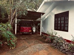 a red car parked in a garage next to a house at The peace place in Ella