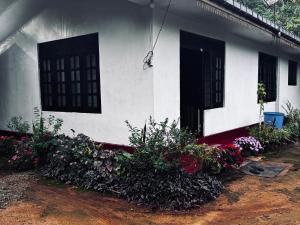 a white house with flowers in front of it at The peace place in Ella
