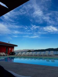 a swimming pool with white chairs and a blue sky at FOZDOVEZ in Souto