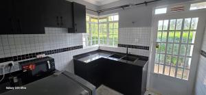 a kitchen with black cabinets and a sink and windows at The Amanda Bed & Breakfast in Migori