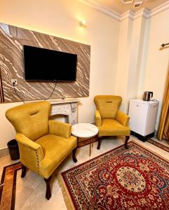 a living room with two chairs and a tv at Super Lodge by HFI in Islamabad