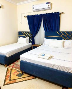 two beds in a room with blue curtains at Super Lodge by HFI in Islamabad