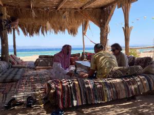 a group of people sitting on the beach at Galuma magbul camp in Dahab +86 photos