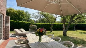 a vase of flowers on a wooden table with chairs at House C - North Sea Stays in De Haan