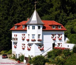 a white building with red roof and flowers on the windows at Hotel Turnerwirt in Salzburg