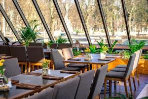 a restaurant with tables and chairs and windows at Radisson Blu Ridzene Hotel, Riga in Riga