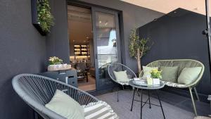 a patio with two wicker chairs and a table with at KRUNA 406 Luxury Sea View Apartment with Parking, Minibar, Spa & Beach - Includes 2 Complimentary Non-Alcoholic Beach Drinks & Welcome Gift in Budva