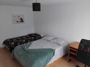 a bedroom with a bed and a table and a television at La Bouvardière, gîte au calme, en pleine campagne, tout près de Rennes in Le Rheu