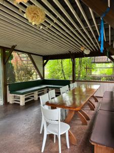 a dining room with a wooden table and white chairs at Гостинний двір Підкова in Budishche