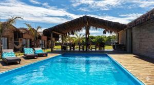 an outdoor swimming pool with a wooden deck and a patio with a table and chairs at Pousada Nitxi Awêry in Caraíva