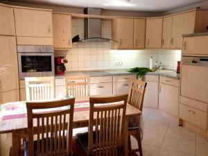a kitchen with a wooden table and chairs and a kitchen with a sink at Apfelblüte - Ferienhaus - ABC321 in Klein Warin